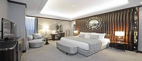 Una habitación de hotel moderna con una cama grande, un escritorio, un sofá, un televisor y un espejo.