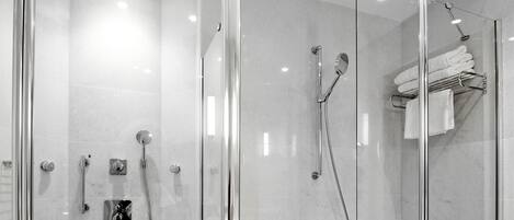 Un baño moderno con ducha acristalada, bañera independiente y lavabo con cerramiento de vidrio.