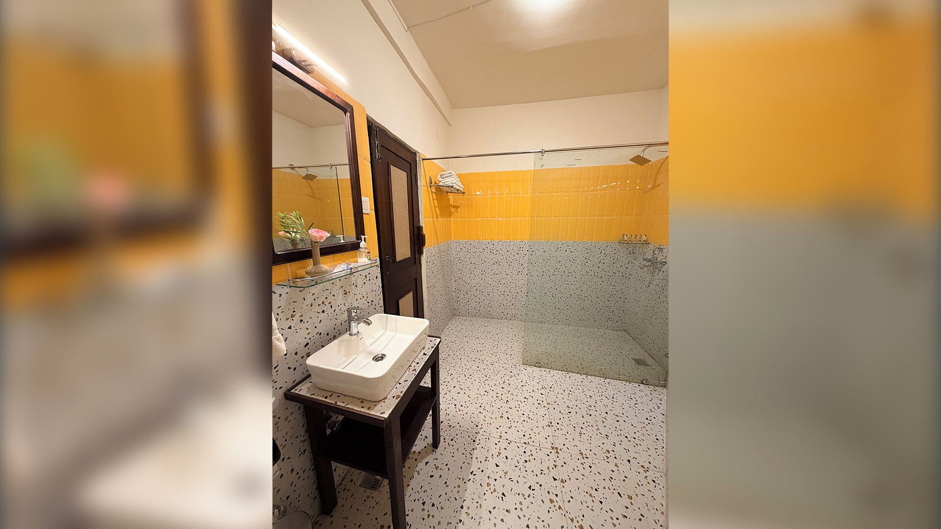 Un baño con lavamanos, espejo y zona de ducha.