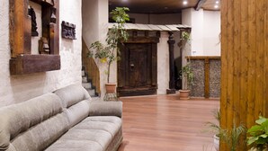 Une pièce spacieuse avec un plafond en bois, un canapé gris et un escalier menant à un autre espace.
