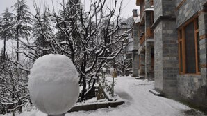Un espace extérieur enneigé avec un bâtiment en pierre et un globe à neige.
