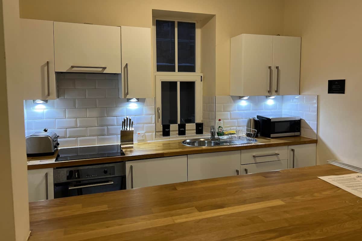 A modern kitchen with white cabinets, a wooden countertop, a microwave, and a toaster.