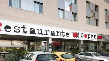 A building with a sign that reads 'Restaurante Open' and a car parked in front.