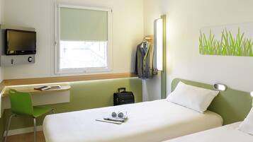 Una habitación de hotel con cama, escritorio, silla, televisión y ventana.