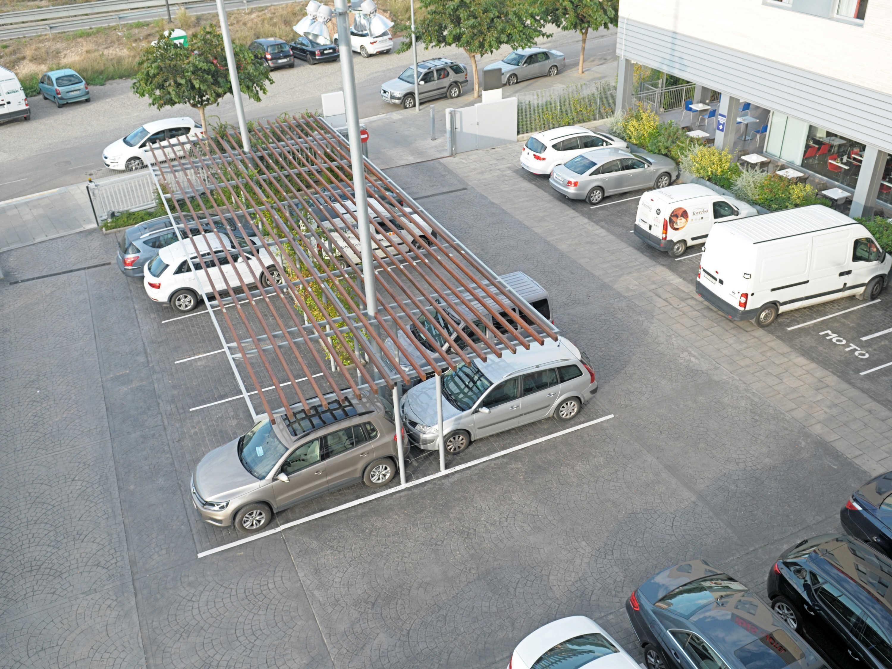 Un parking contenant plusieurs voitures et une zone de stationnement couverte.