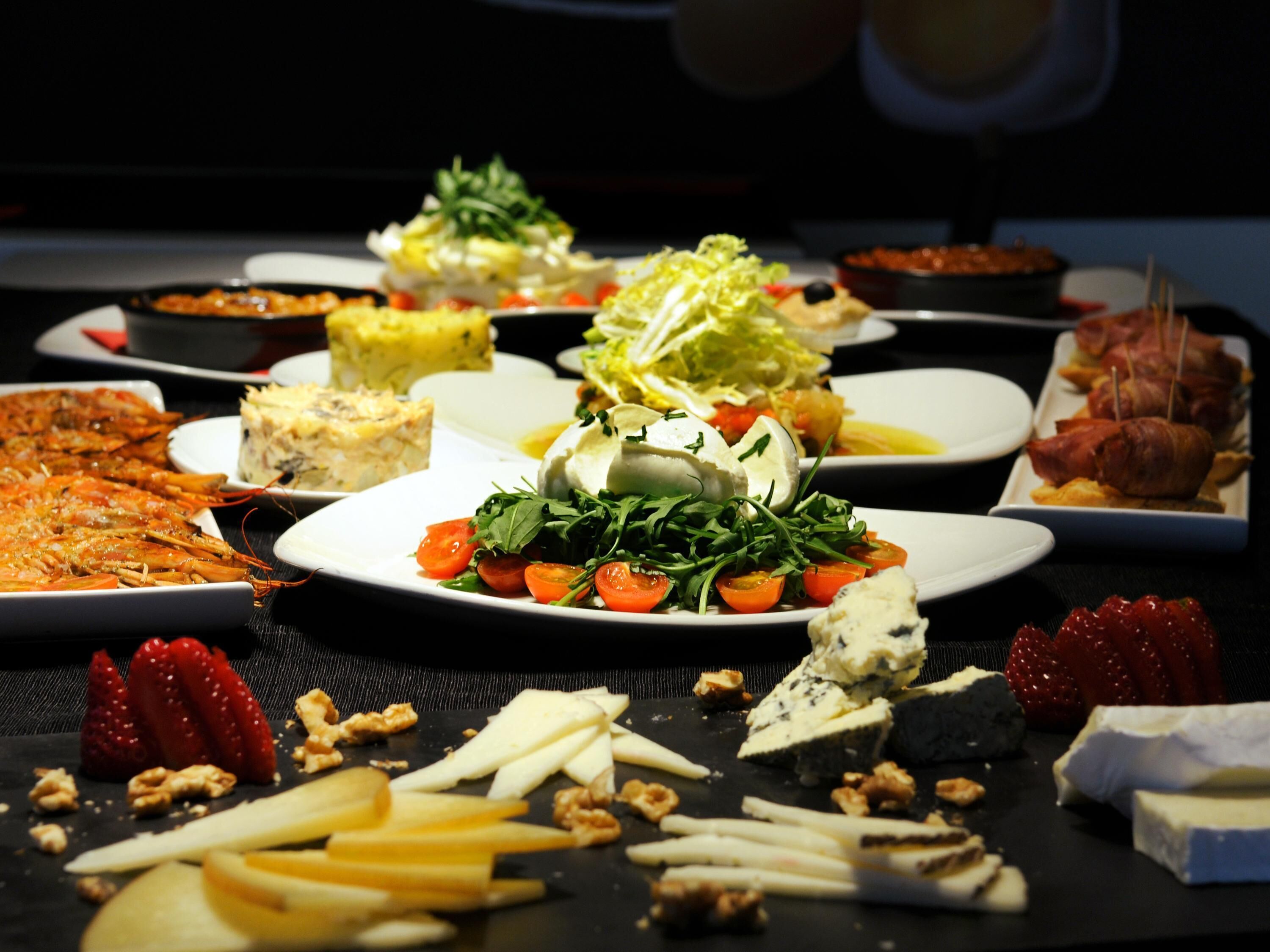 Una variedad de platos en una mesa, como ensaladas, quesos y carnes.