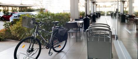A covered outdoor seating area with a bicycle and a shopping cart.