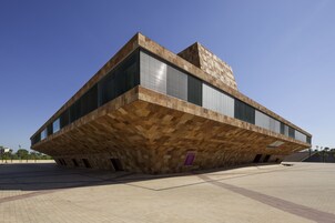 Un edificio moderno con un diseño angular distintivo, que combina ladrillo y vidrio.