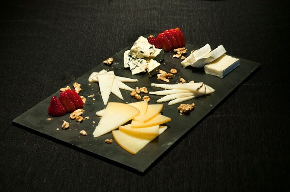 A black slate board with various cheeses, strawberries, and walnuts. - ibis Lleida (Lleida)