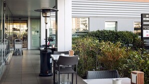 An outdoor seating area with tables and chairs, a trash bin, and a decorative lamp. - ibis Lleida (Lleida)