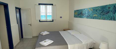 Une chambre à coucher comprenant un lit, une table de chevet, une fenêtre avec vue et une œuvre d’art murale.