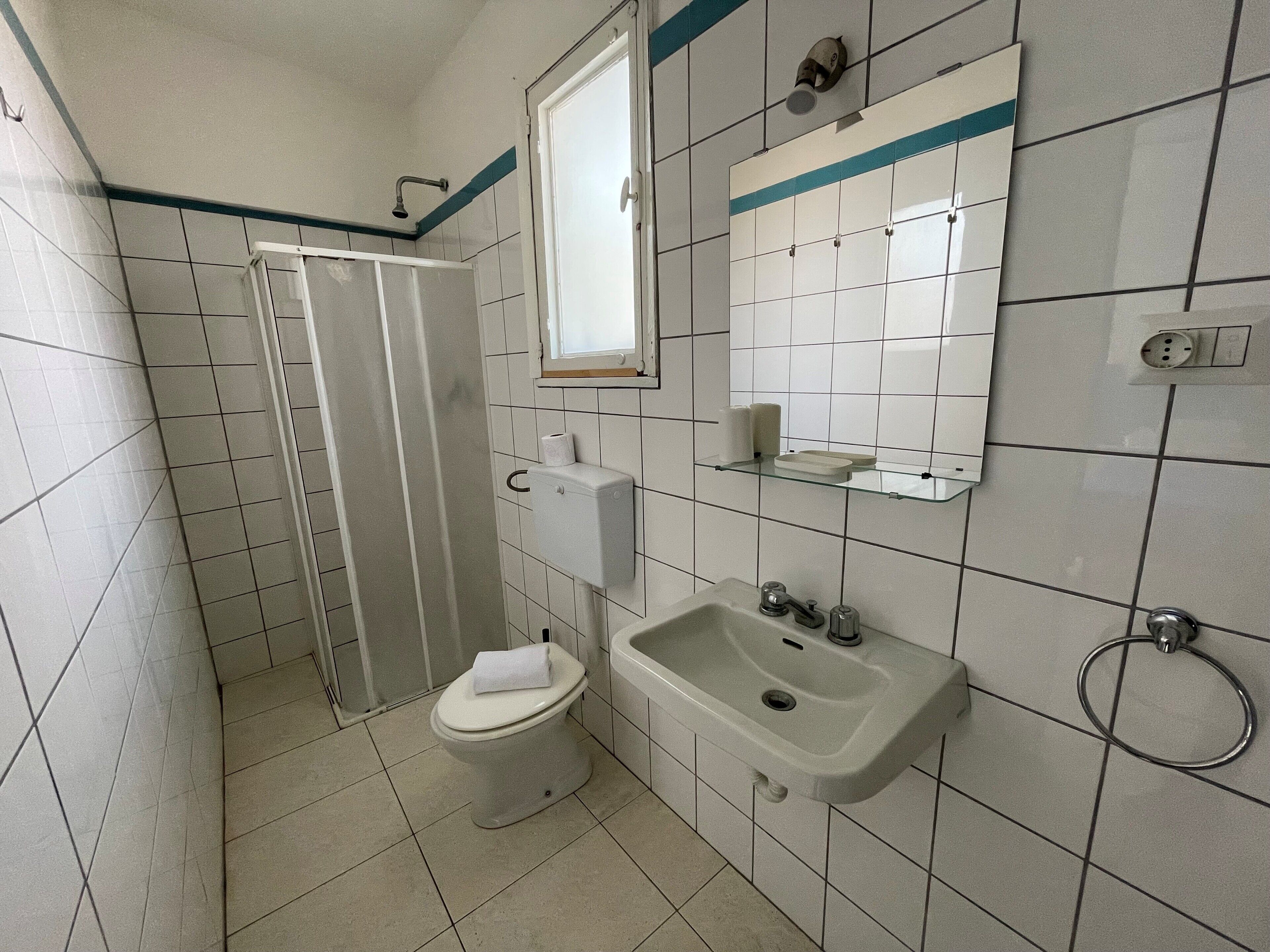 Un baño pequeño con azulejos, un inodoro, un lavabo y una ducha.