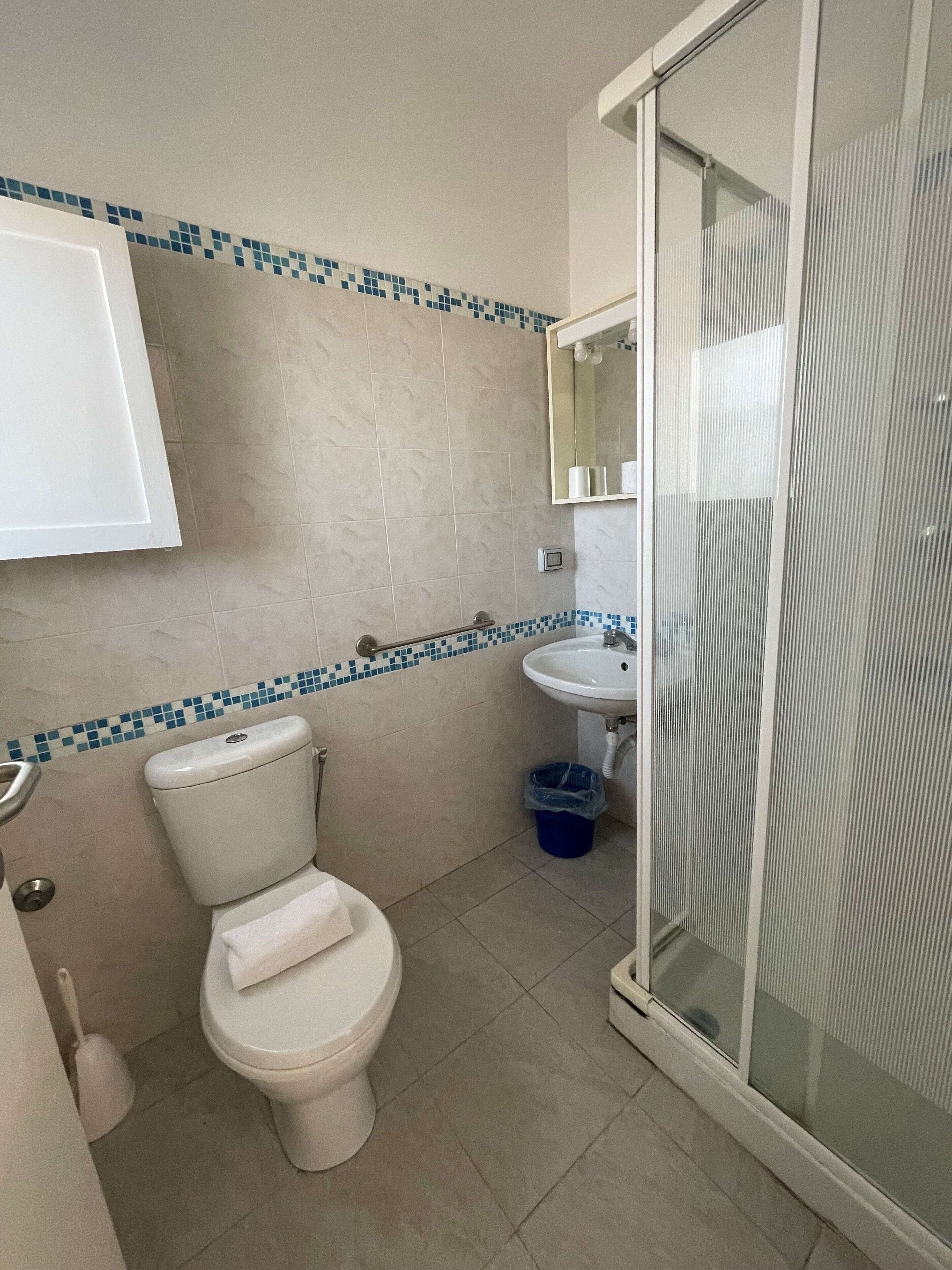 Une salle de bain comprenant des toilettes, un lavabo et un espace douche.