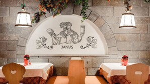 A restaurant interior with a stone wall, two hanging light fixtures, and a central mural with the name "JANVS".