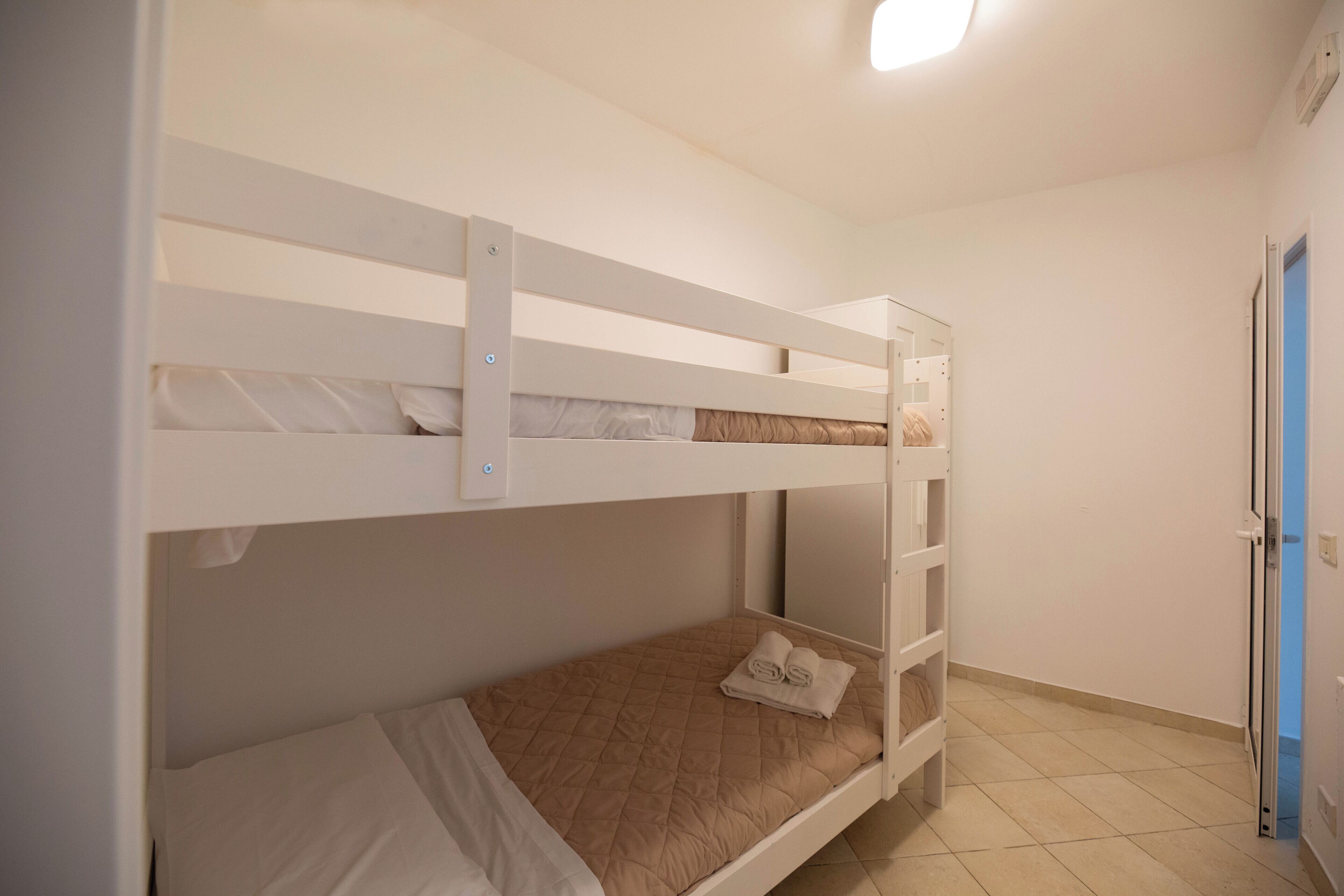 Dormitorio con literas, puerta y lámpara.