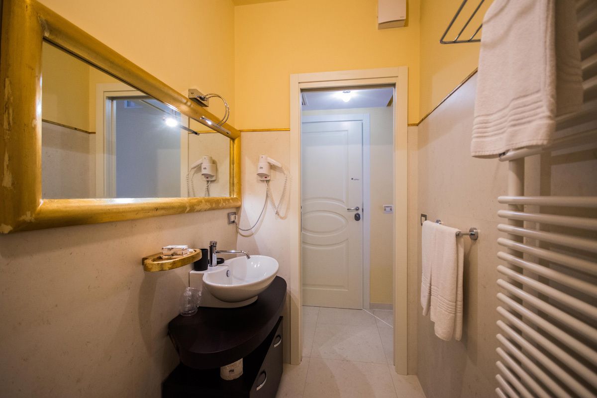 A bathroom with a sink, mirror, and towel rack.