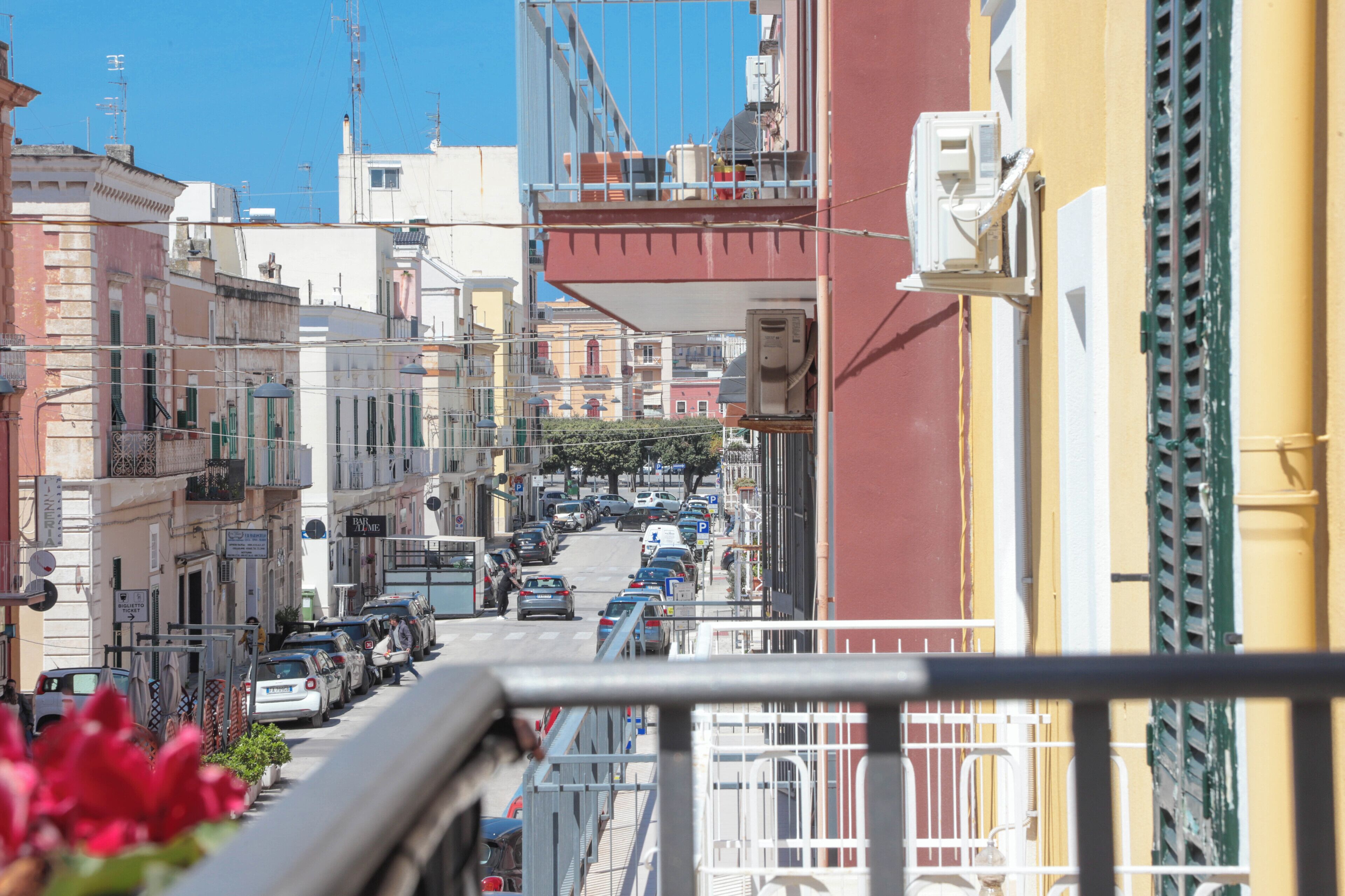 A narrow street with parked cars and buildings on both sides.