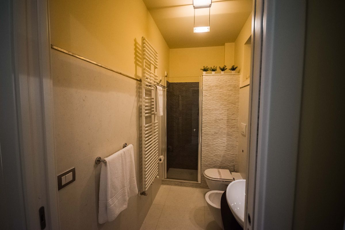 Un baño pequeño con ducha, inodoro y barra para toallas.