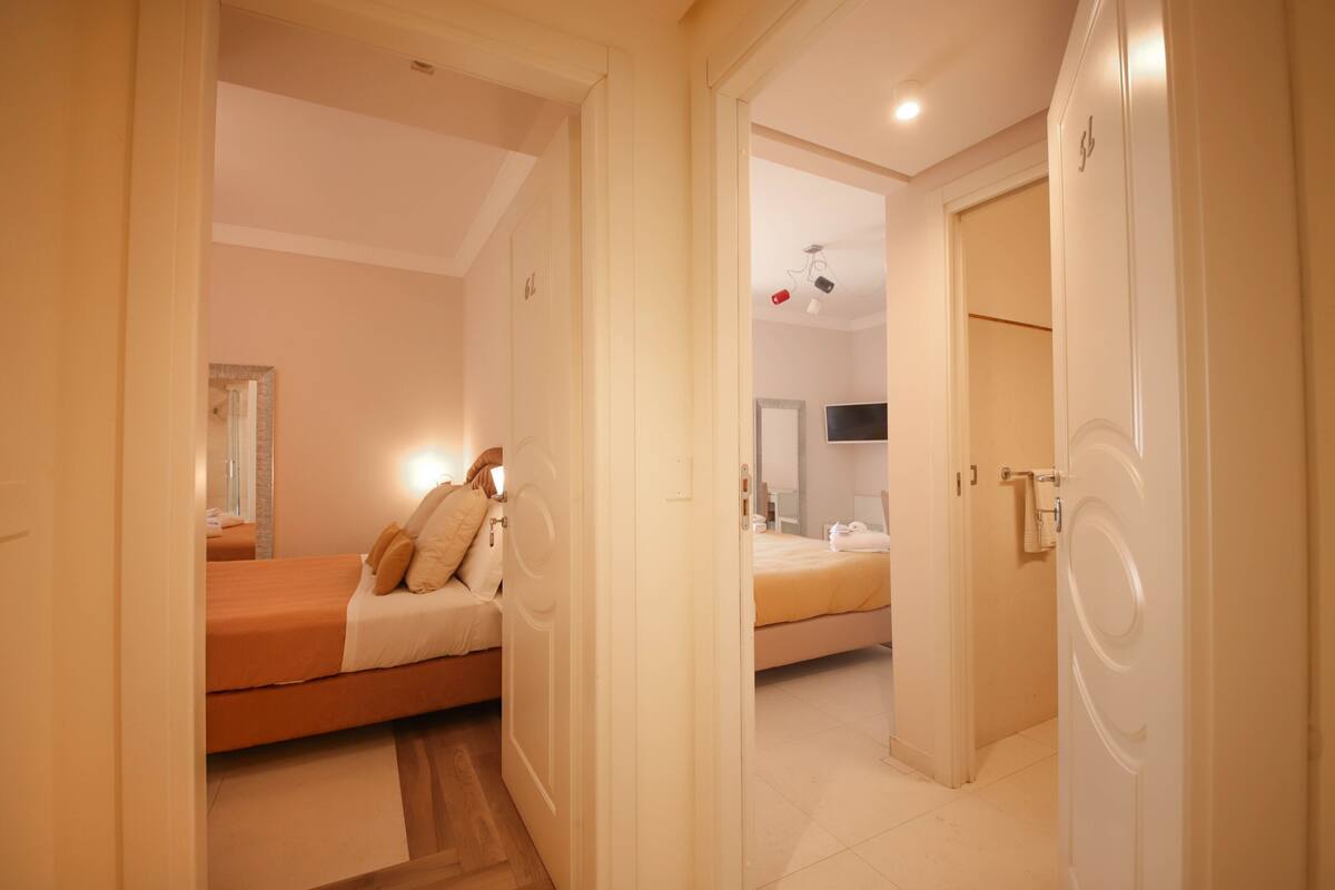 Une chambre d’hôtel avec deux lits, une salle de bain et un couloir.