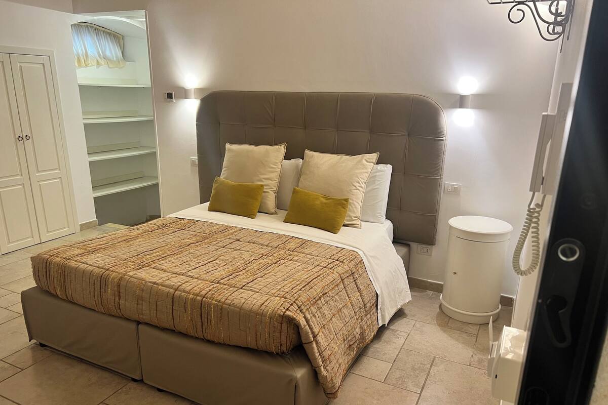 Une chambre à coucher comprenant un lit, une table de chevet, une armoire et une salle de bain avec des toilettes.