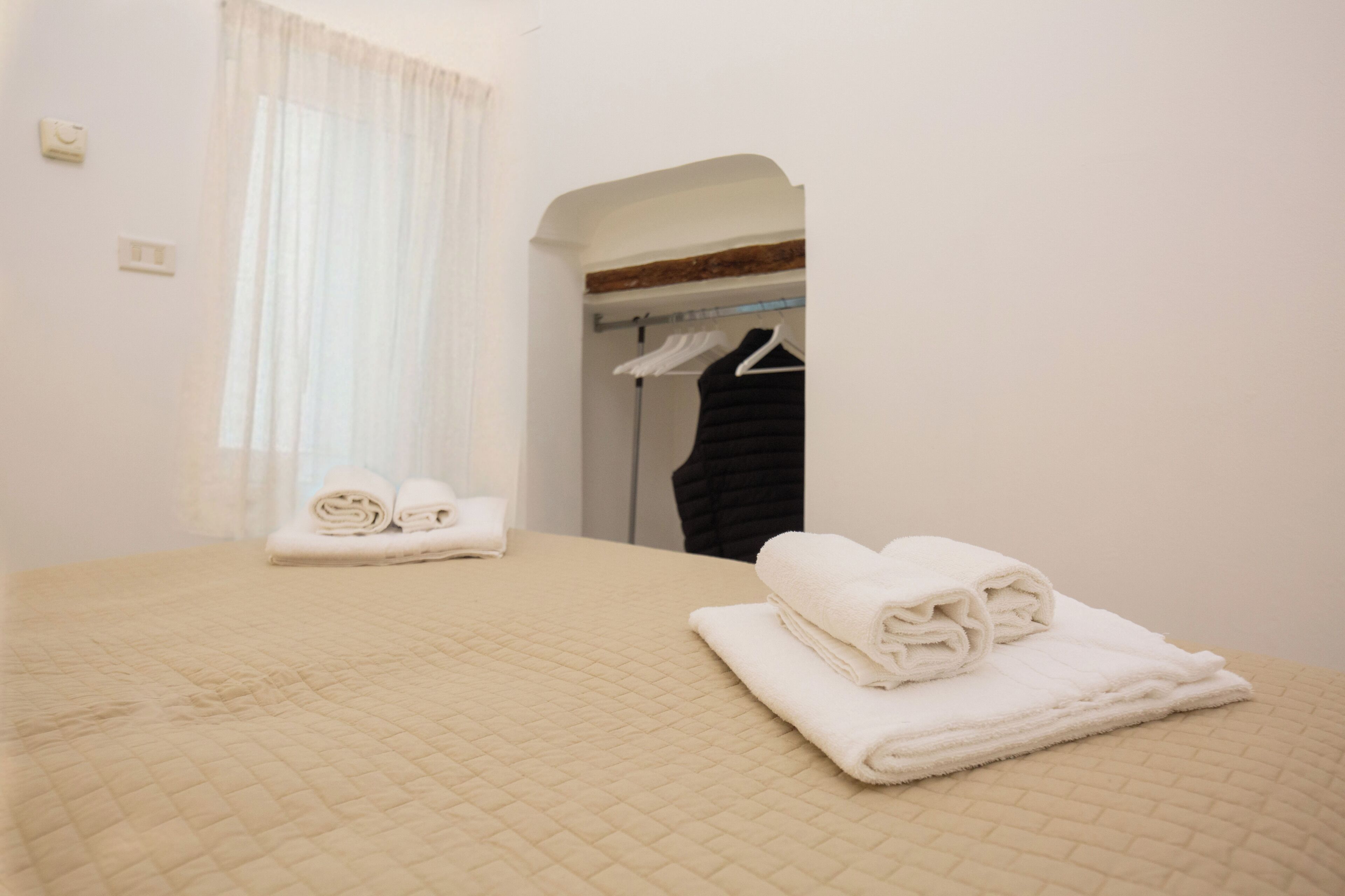 A hotel room with a bed, a closet, and a window with curtains.