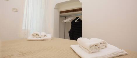 A hotel room with a bed, a closet, and a window with curtains.