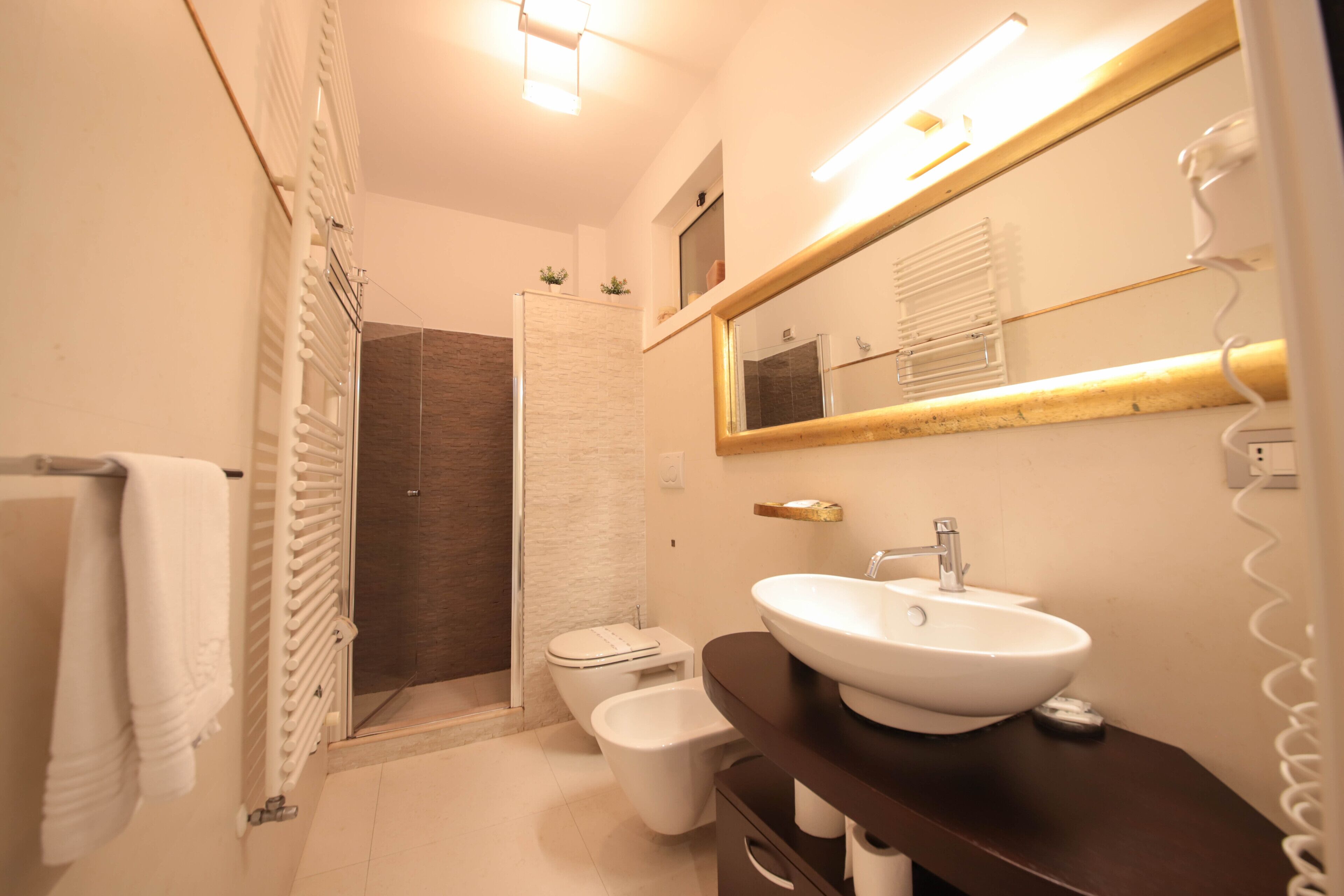 A modern bathroom with a white sink, a large mirror, and a shower area.