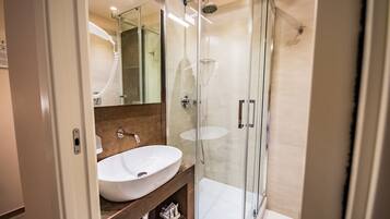 Une salle de bain moderne avec une douche à parois de verre, un grand lavabo blanc et un miroir.
