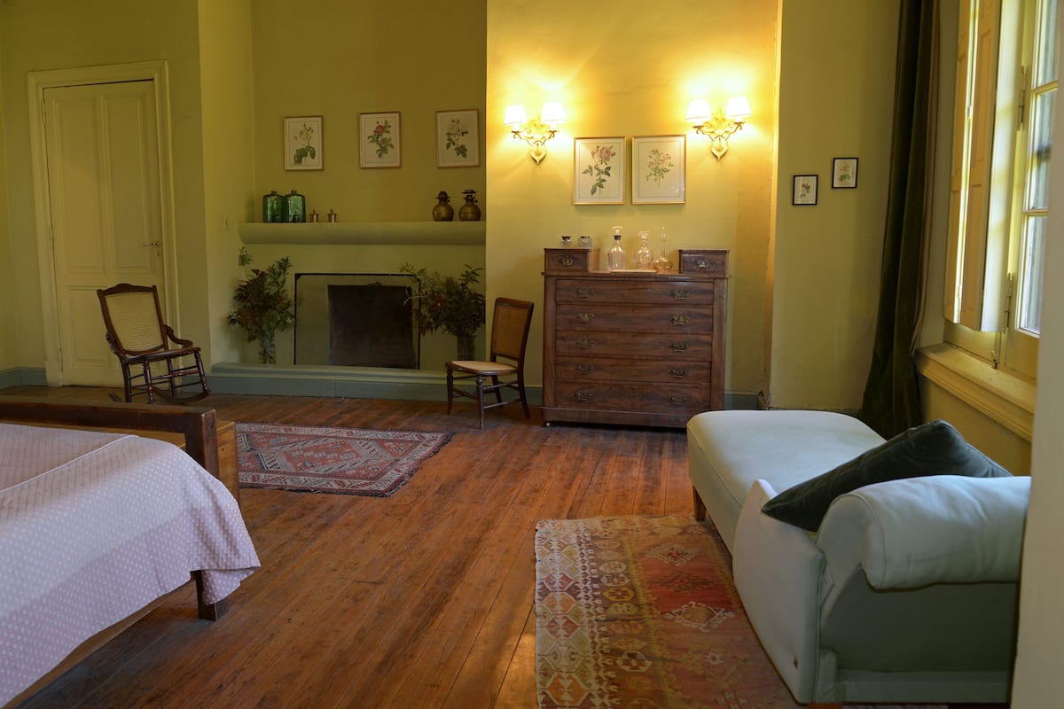 A room with a fireplace, wooden furniture, and wall-mounted lighting.