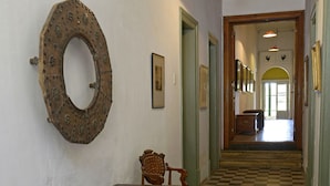 A hallway with a checkered floor, a wooden bench, a table with bowls, and a decorative mirror on the wall.