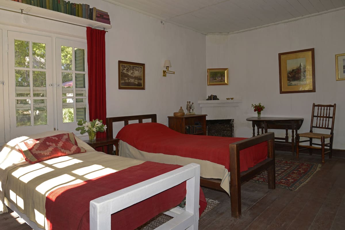A room with two single beds, a fireplace, a desk, and a chair.