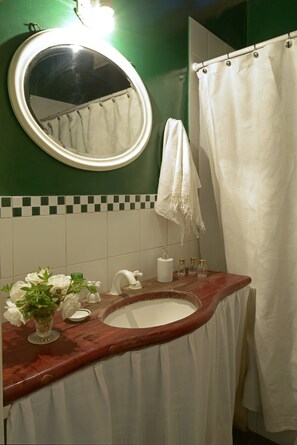 A bathroom with a round mirror, green walls, a white sink, a white towel, and a shower curtain.