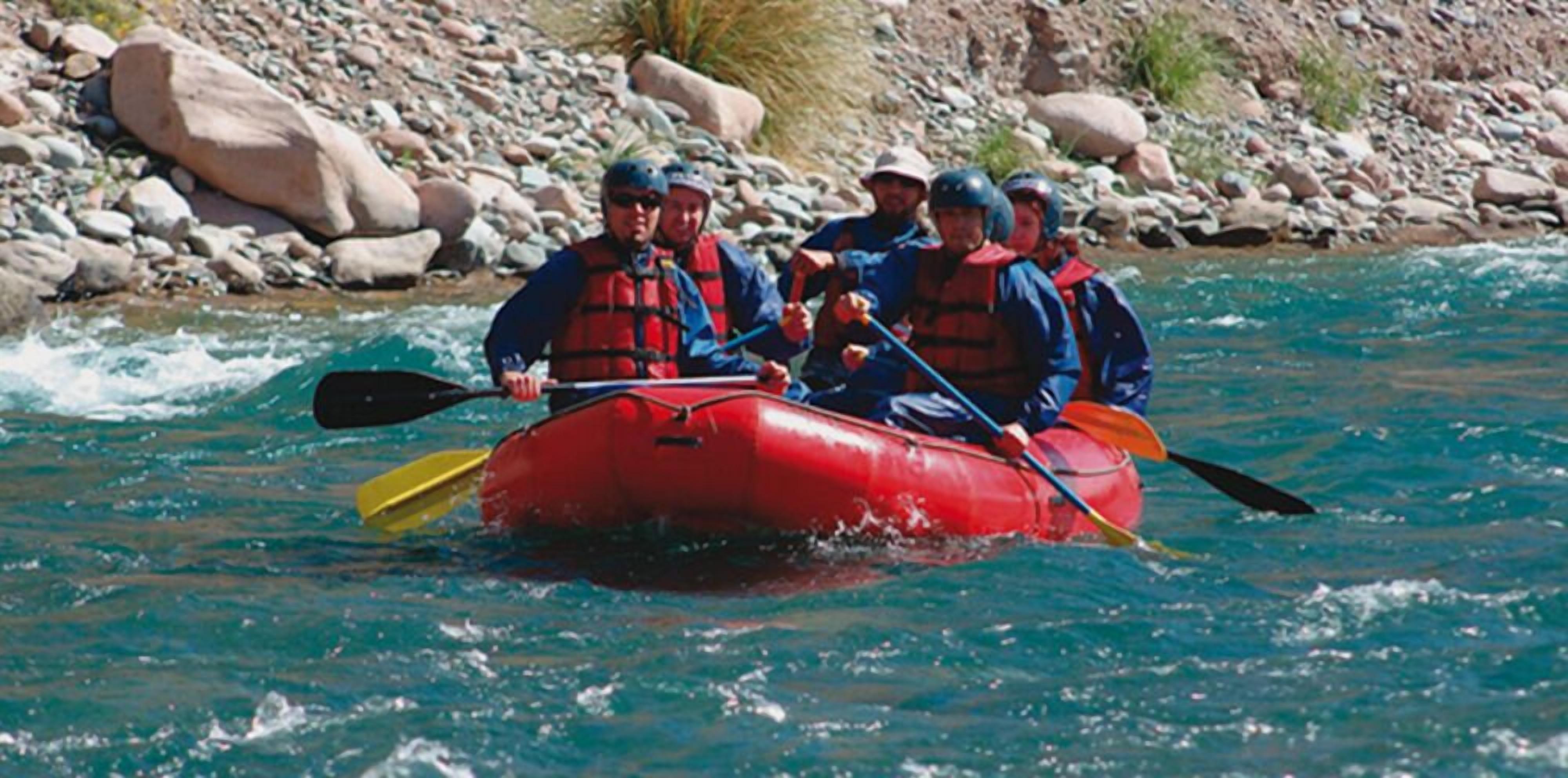 Een groep mensen in een rode opblaasboot op een rivier.