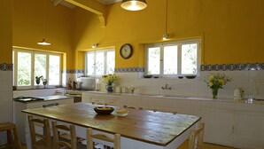 A kitchen with a wooden table, chairs, a stove, and a clock on the wall.