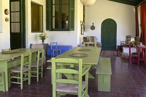 A dining area with a long table and multiple chairs, a bench, and a door with a green frame.