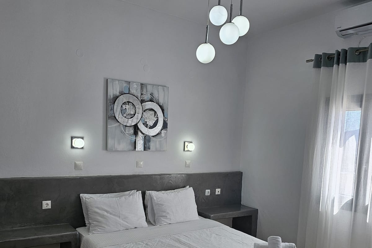 Ein modernes Hotelzimmer mit einem großen Bett, Nachttischen, einem Wandbild und einer Deckenleuchte.