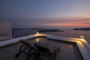 A rooftop terrace with lounge chairs and a pool, overlooking a body of water and distant islands. - Folia Bianca Apartments (Santorini)