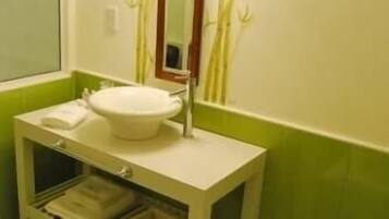 Un baño con un lavabo blanco, un espejo y paredes verdes.