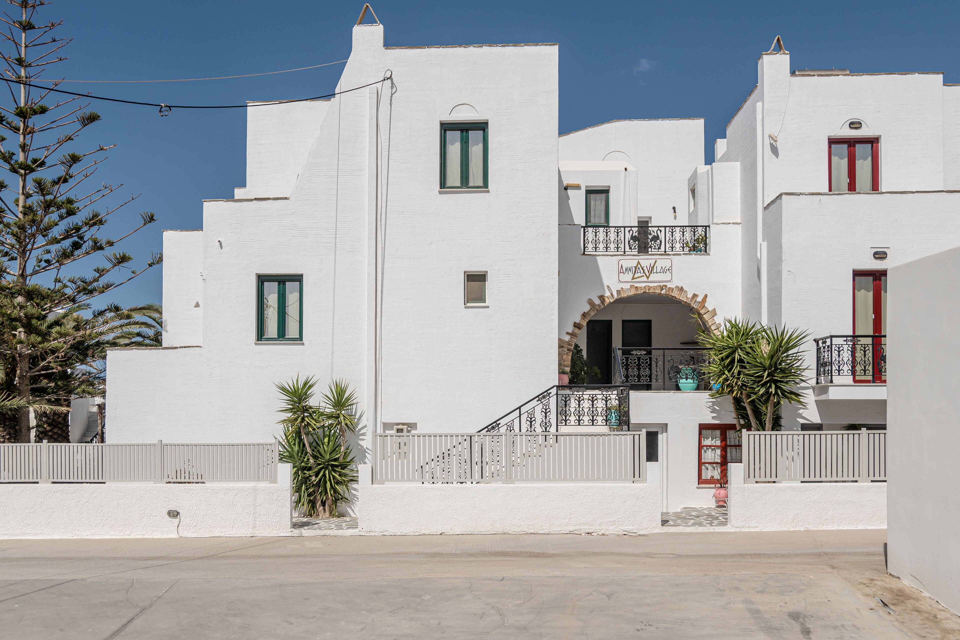 A white building with a balcony, a small entrance, and a sign above the door.