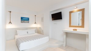 Un dormitorio con cama, lámparas de noche, televisor montado, espejo y un cuadro en la pared.