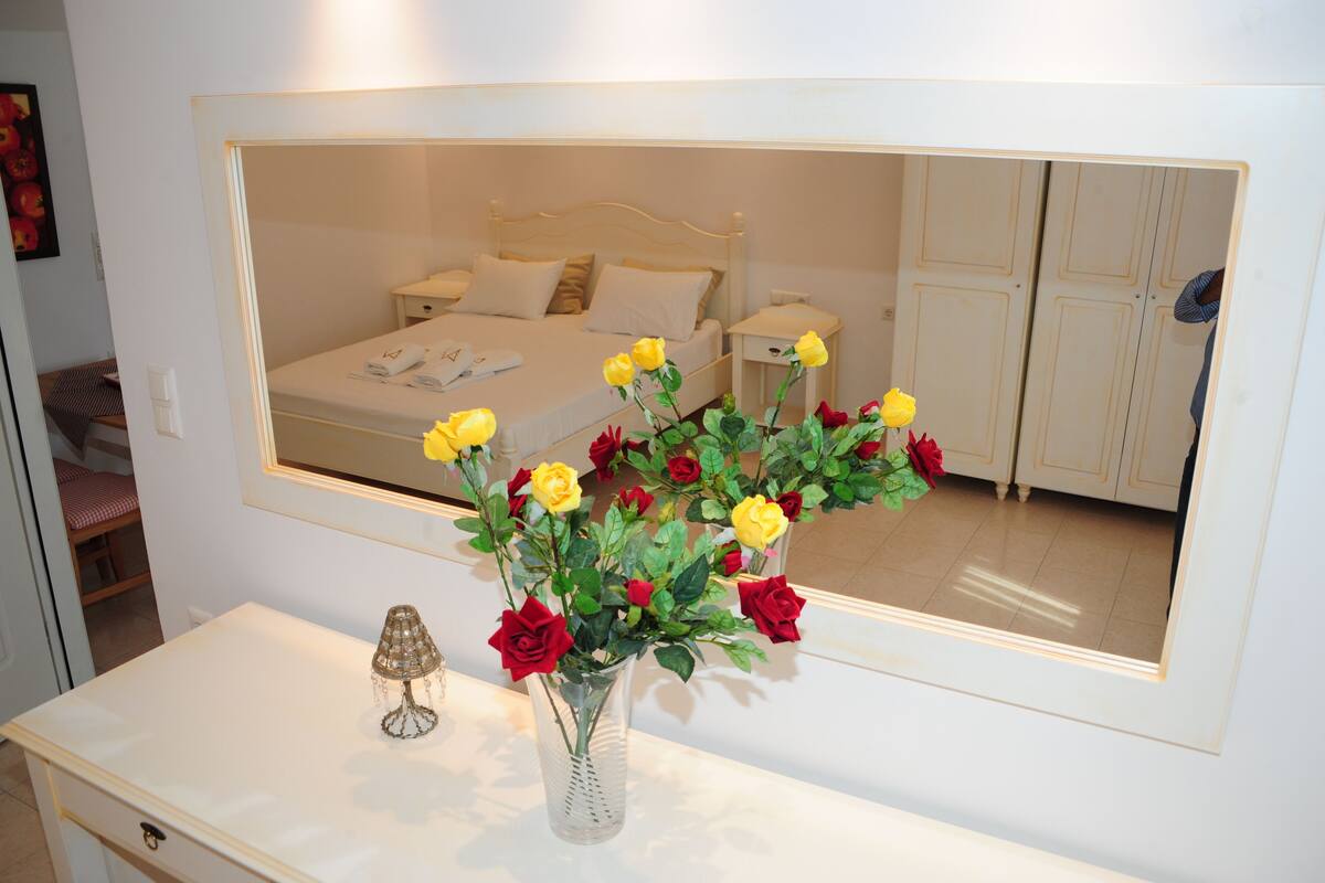 A bedroom with a bed, nightstands, and a mirror reflecting the room.