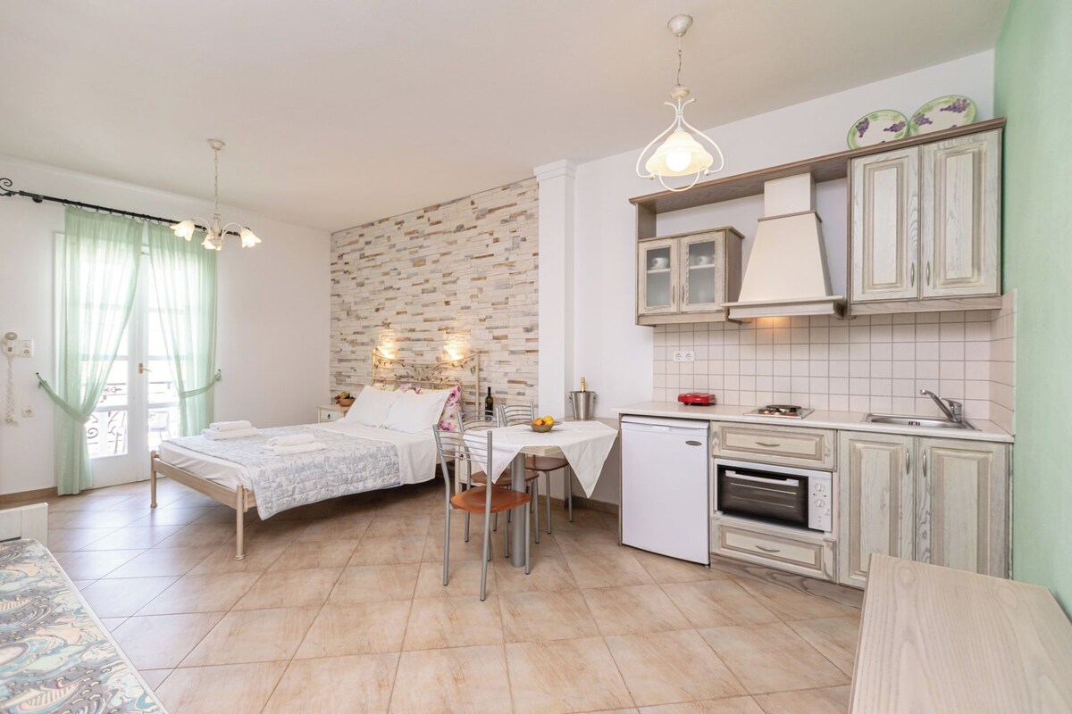 Una habitación pequeña con cama, mesa de comedor y kitchenette.