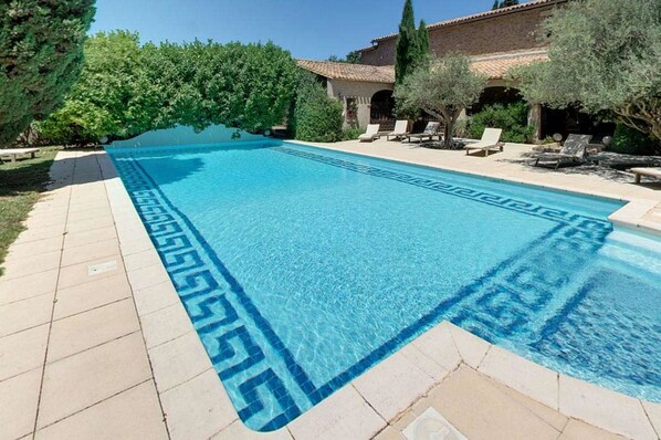 Una piscina al aire libre, sillones reclinables de piscina