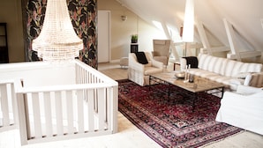 Um amplo quarto no estilo loft, com uma janela grande, um berço branco, um sofá e uma mesa de centro.