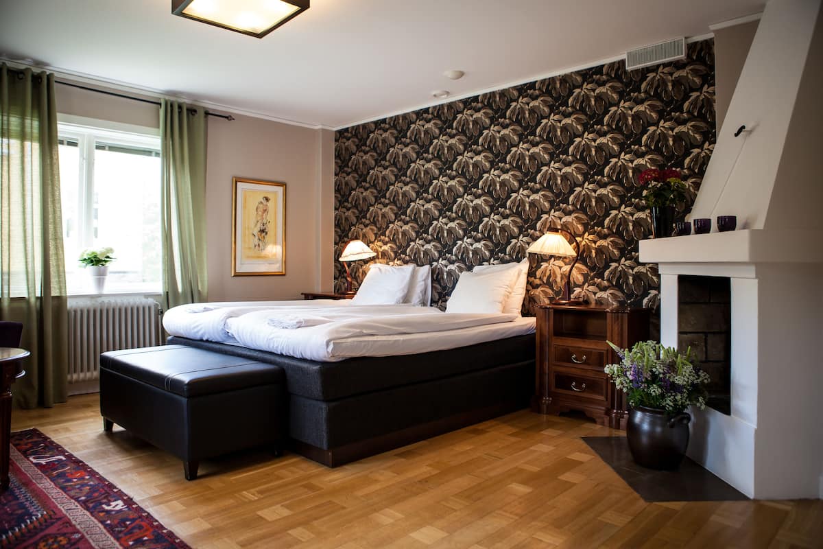 A modern bedroom with a large bed, a fireplace, and a patterned wall.