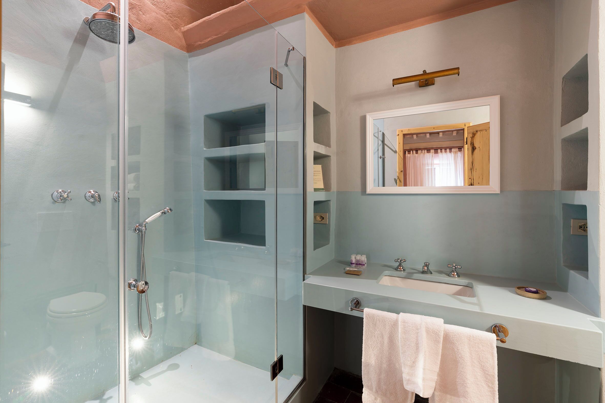 A modern bathroom with a glass-enclosed shower, a white sink, and a mirror above the vanity.