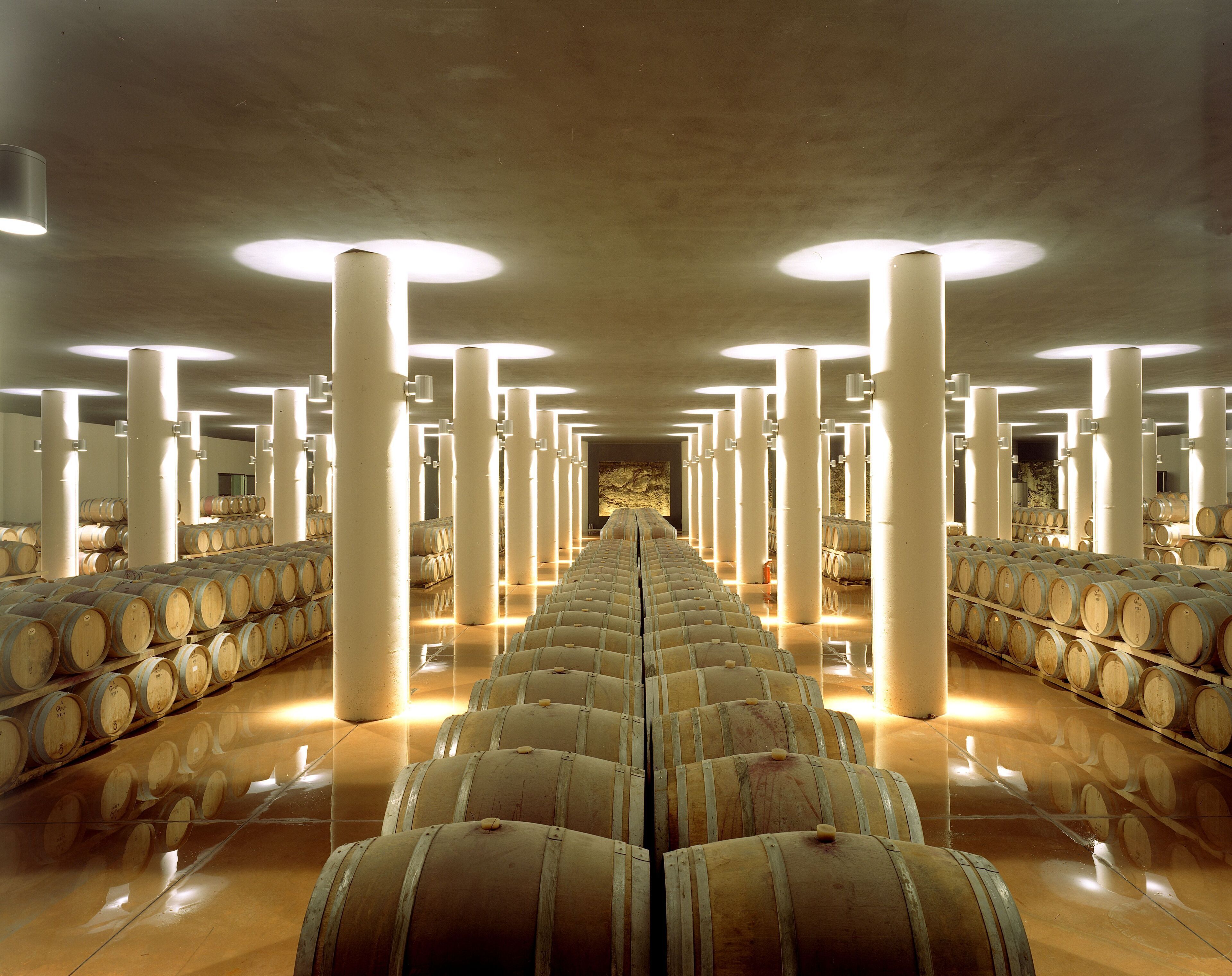 A long corridor lined with wooden barrels under bright ceiling lights.