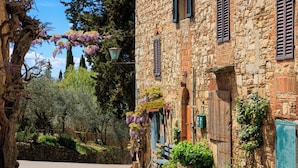 A stone building with wooden shutters, a bench, and hanging purple flowers. - Castello di Fonterutoli Wine Resort (Castellina in Chianti)