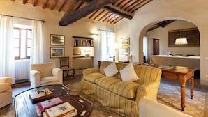 A cozy living room with a striped sofa, a wooden coffee table, and a bookshelf. - Castello di Fonterutoli Wine Resort (Castellina in Chianti)