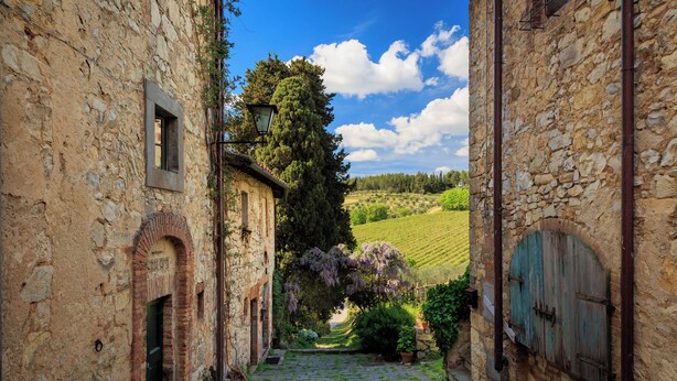 A narrow stone pathway leading to a rustic building with a wooden door and a window. - Castello di Fonterutoli Wine Resort (Castellina in Chianti)